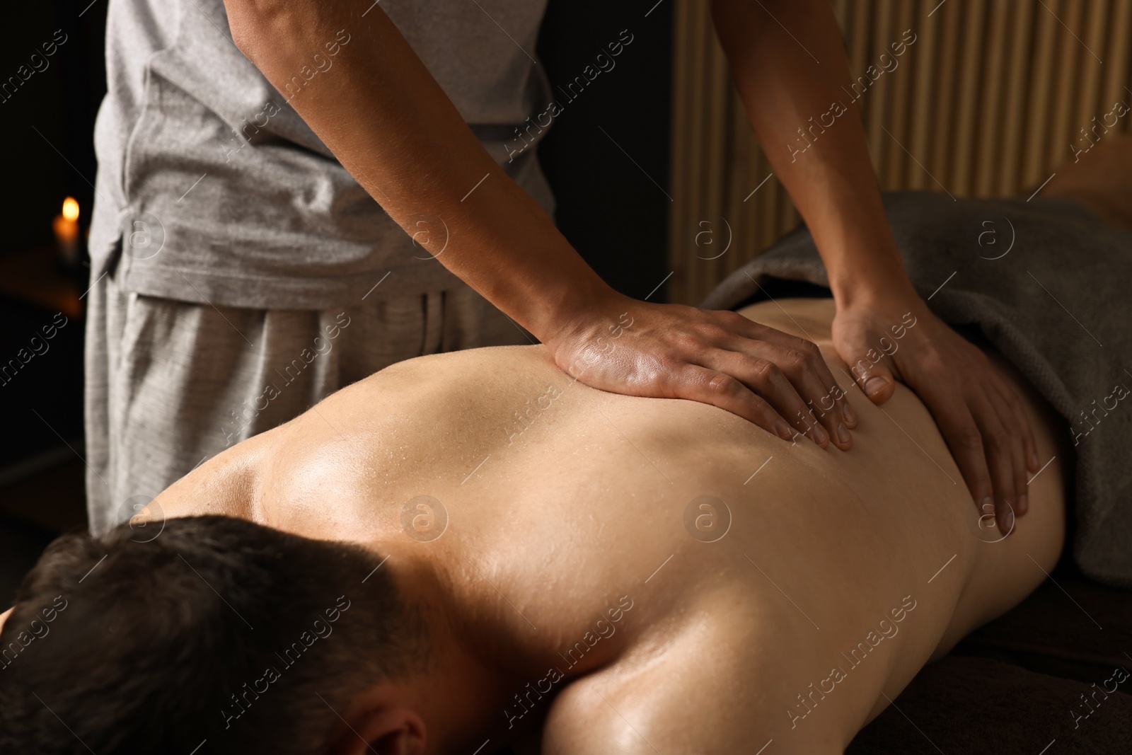 Photo of Professional physiotherapist doing back massage for his client indoors, closeup