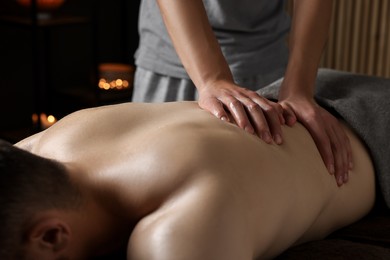 Photo of Professional physiotherapist doing back massage for his client indoors, closeup