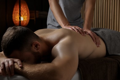 Photo of Professional physiotherapist doing back massage for his client indoors, closeup