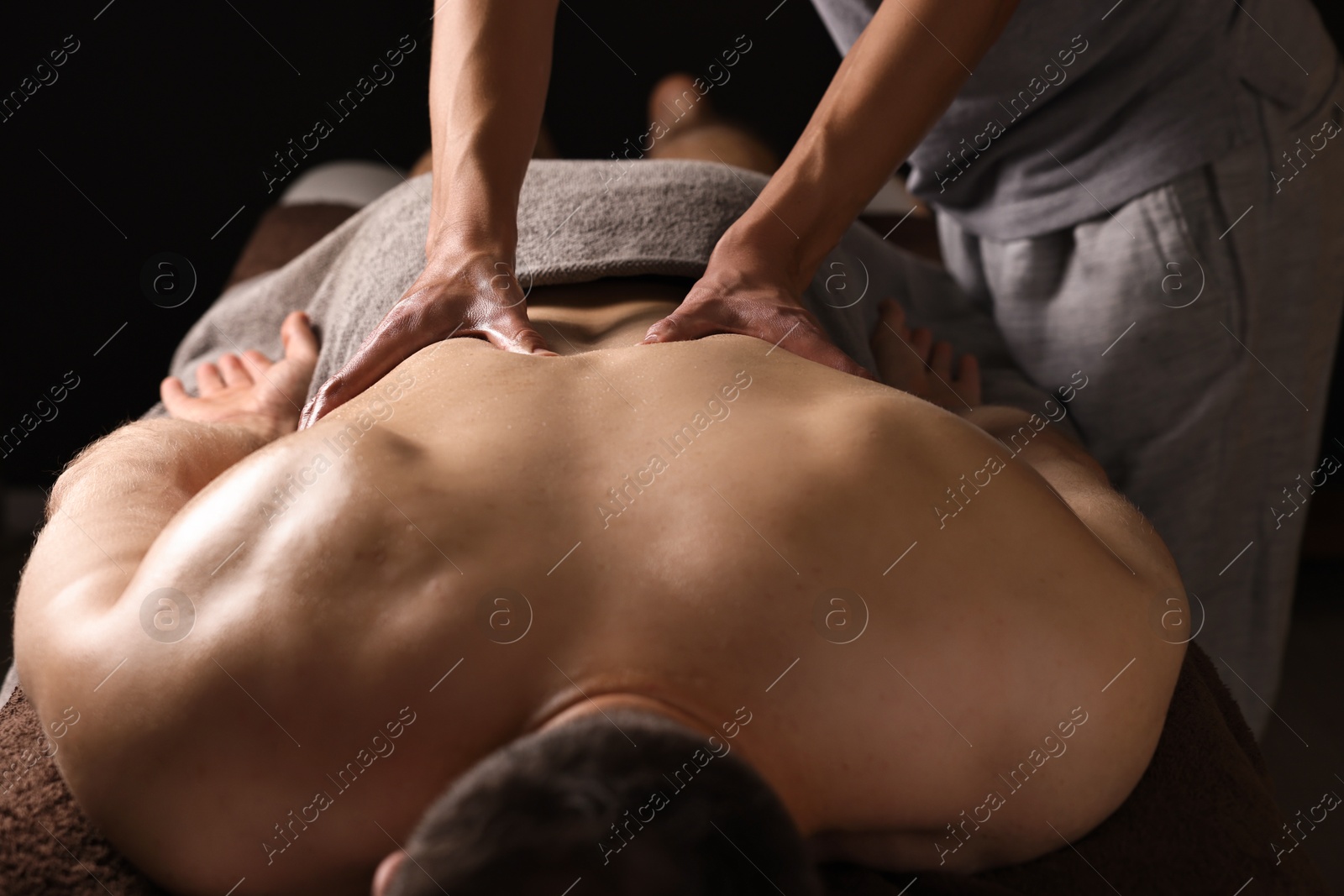 Photo of Professional physiotherapist doing back massage for his client indoors, closeup