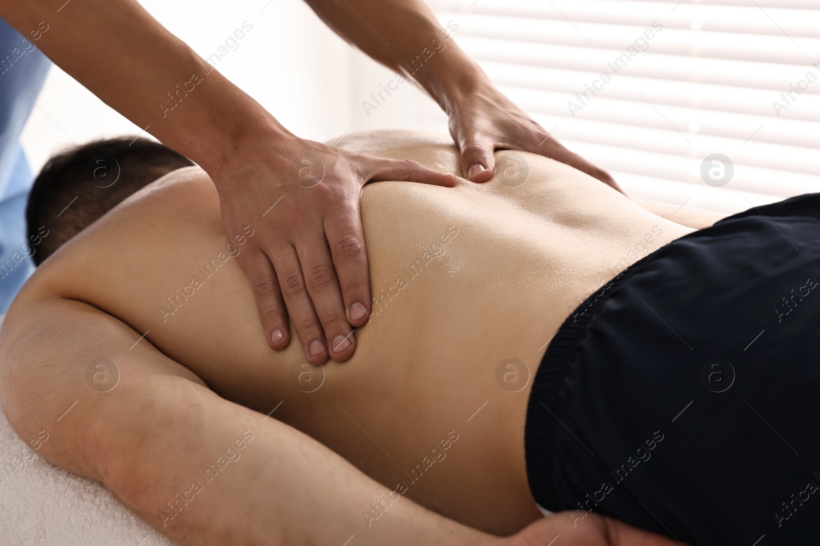 Photo of Professional physiotherapist doing back massage for his client indoors, closeup