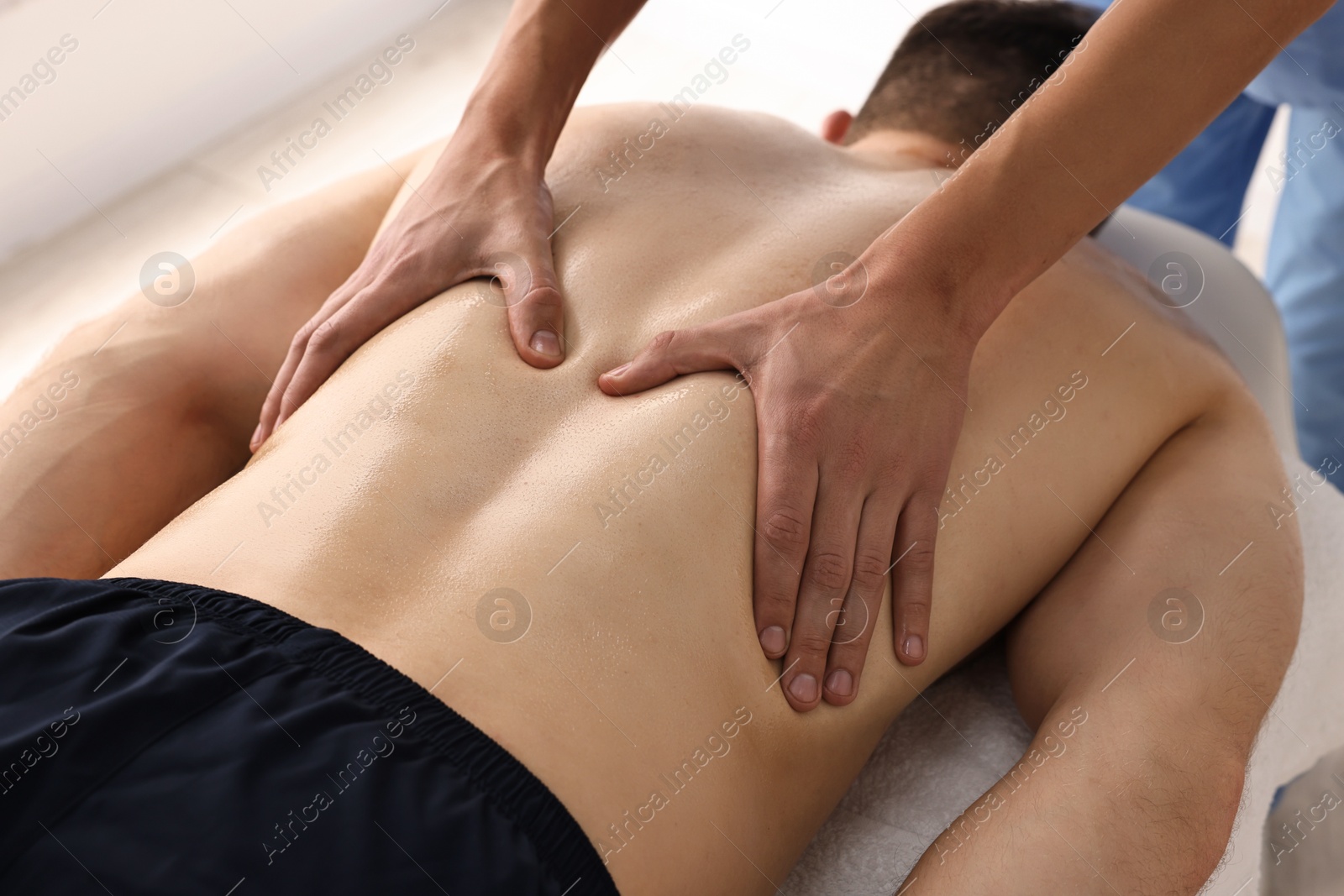 Photo of Professional physiotherapist doing back massage for his client indoors, closeup