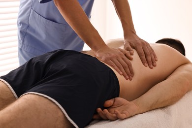 Photo of Professional physiotherapist doing back massage for his client indoors, closeup