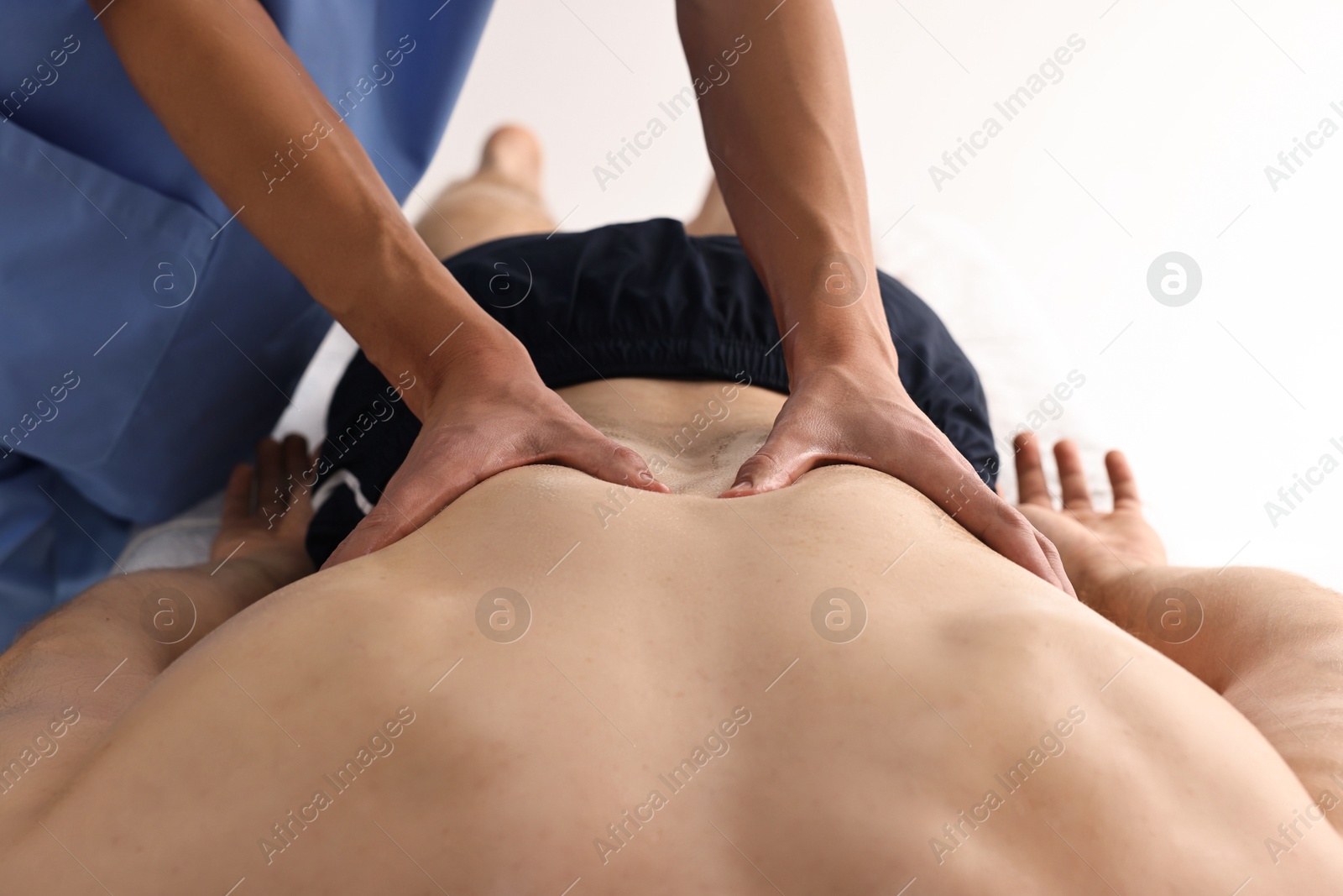 Photo of Professional physiotherapist doing back massage for his client indoors, closeup