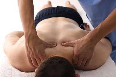 Photo of Professional physiotherapist doing neck massage for his client indoors, closeup