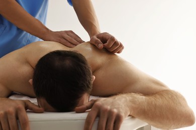 Photo of Professional physiotherapist doing back massage for his client indoors, closeup