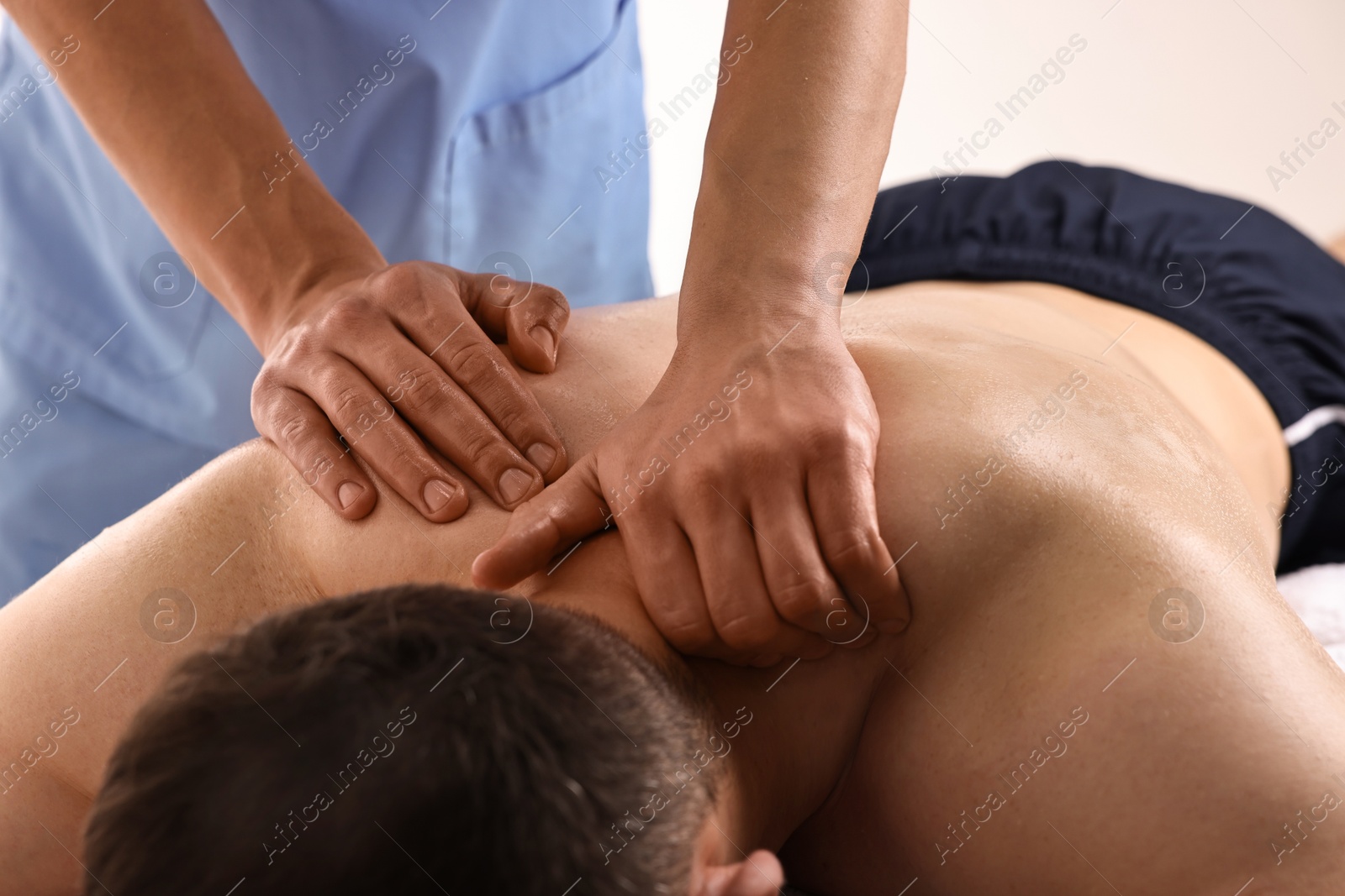 Photo of Professional physiotherapist doing neck massage for his client indoors, closeup