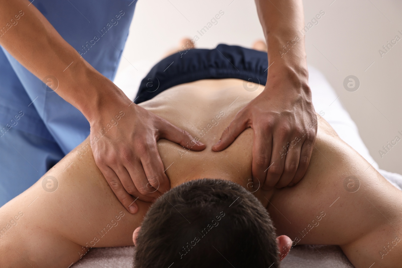 Photo of Professional physiotherapist doing neck massage for his client indoors, closeup