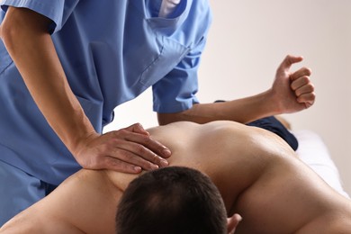 Professional physiotherapist doing back massage for his client indoors, closeup