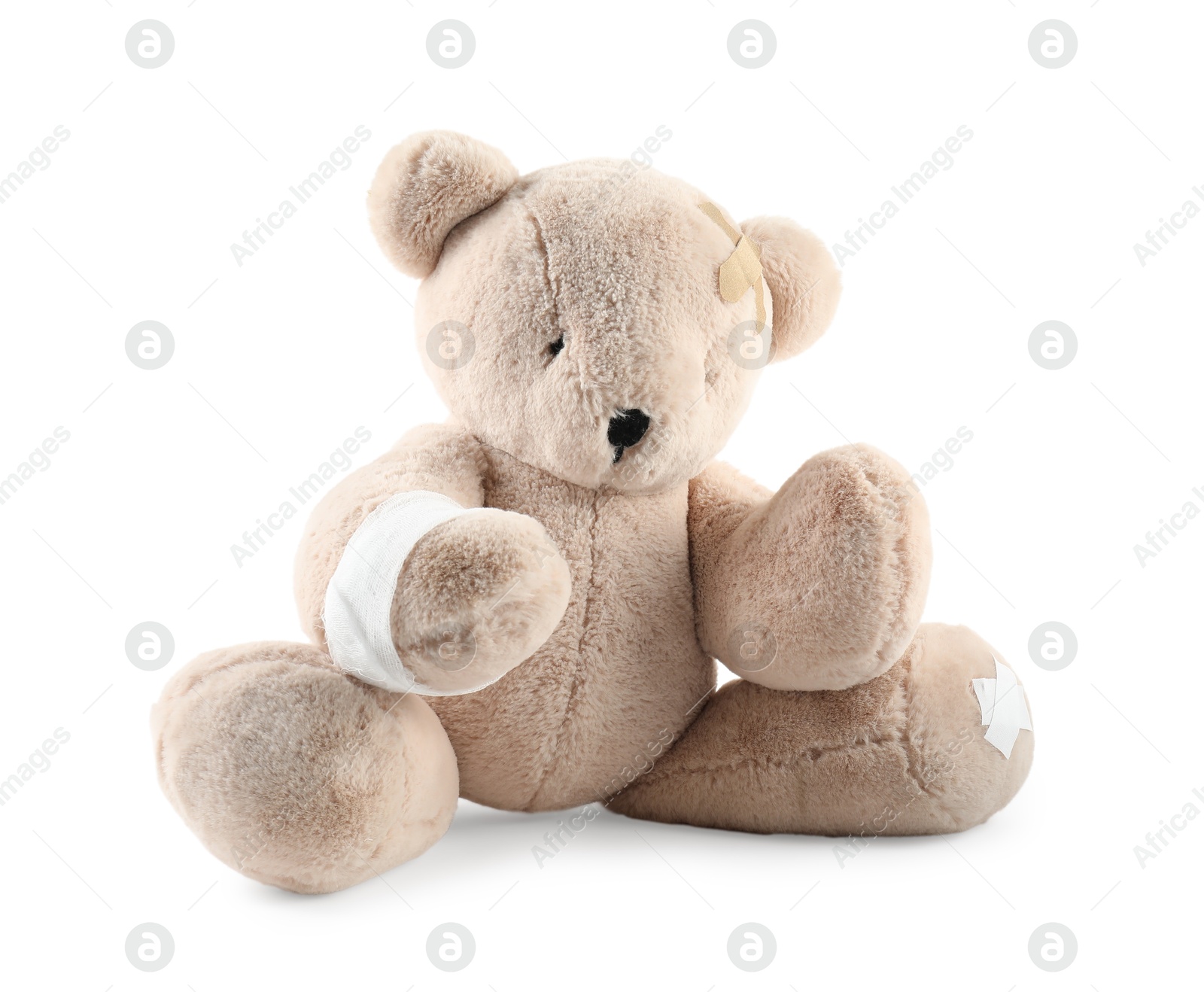 Photo of Teddy bear with bandages and adhesive medical plasters isolated on white