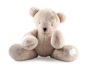 Photo of Teddy bear with bandages and adhesive medical plasters isolated on white