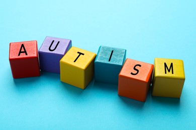 Photo of Word Autism made of colorful cubes on light blue background