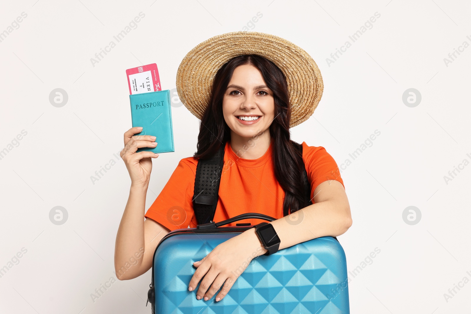 Photo of Young tourist in hat with suitcase, passport and ticket on white background