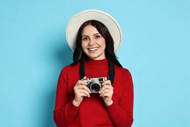 Photo of Young tourist in hat with camera on light blue background