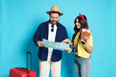 Photo of Tourism. Happy couple with map and suitcase on light blue background