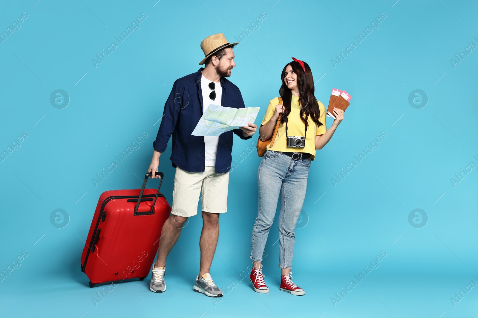 Photo of Tourism. Happy couple with map and suitcase on light blue background