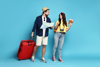 Tourism. Happy couple with map and suitcase on light blue background