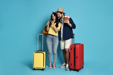 Photo of Tourism. Happy couple with suitcases on light blue background