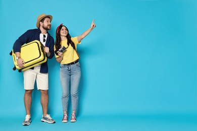 Tourism. Happy couple with suitcase on light blue background, space for text