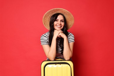 Photo of Young tourist in hat with suitcase on red background