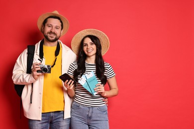 Photo of Tourism. Happy couple in hats with camera, passports and tickets on red background, space for text