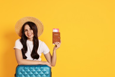 Photo of Young tourist in hat with suitcase, passport and ticket on yellow background, space for text