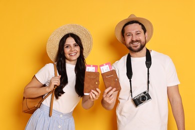 Tourism. Happy couple in hats with passports and tickets on yellow background