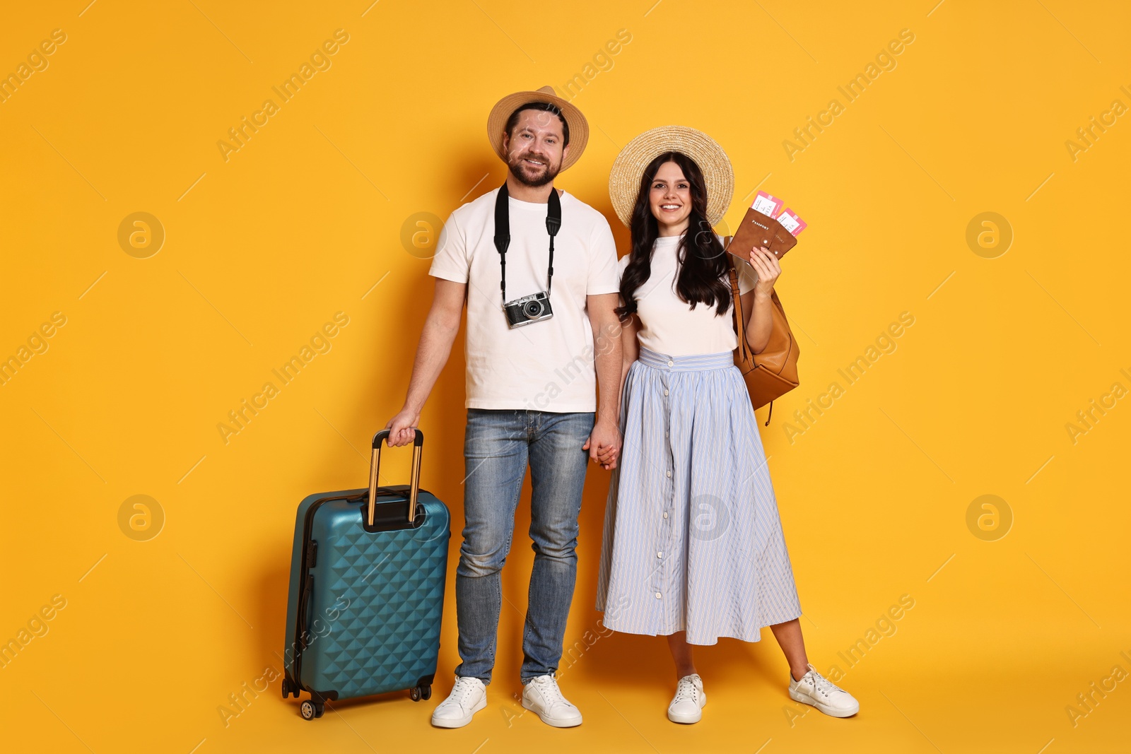 Photo of Tourism. Happy couple in hats with suitcase, passports and tickets on yellow background