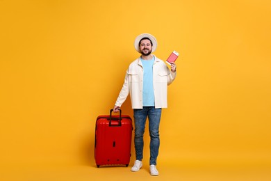 Traveller with suitcase, passport and ticket on orange background