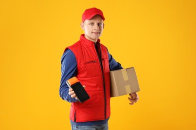 Photo of Happy courier with payment terminal and parcel on yellow background