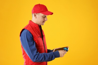 Courier with payment terminal and debit card on yellow background