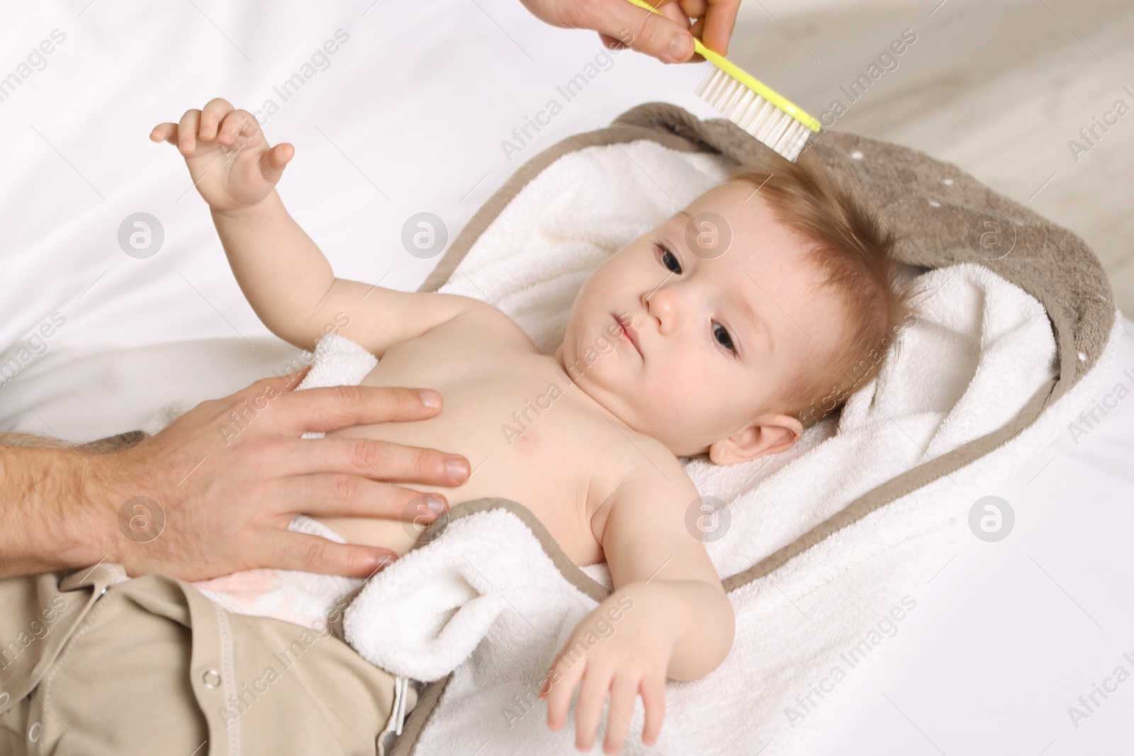 Photo of Man brushing hair of his little baby indoors, closeup