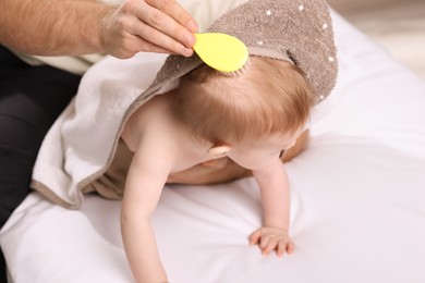 Photo of Man brushing hair of his little baby indoors, closeup