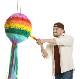 Happy man hitting colorful pinata with stick on white background