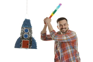 Photo of Happy man hitting rocket shaped pinata with stick on white background