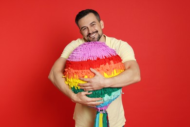 Happy man with colorful pinata on red background