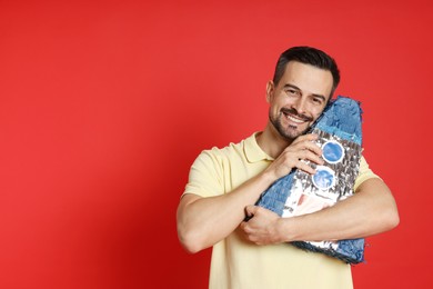 Happy man with rocket shaped pinata on red background, space for text