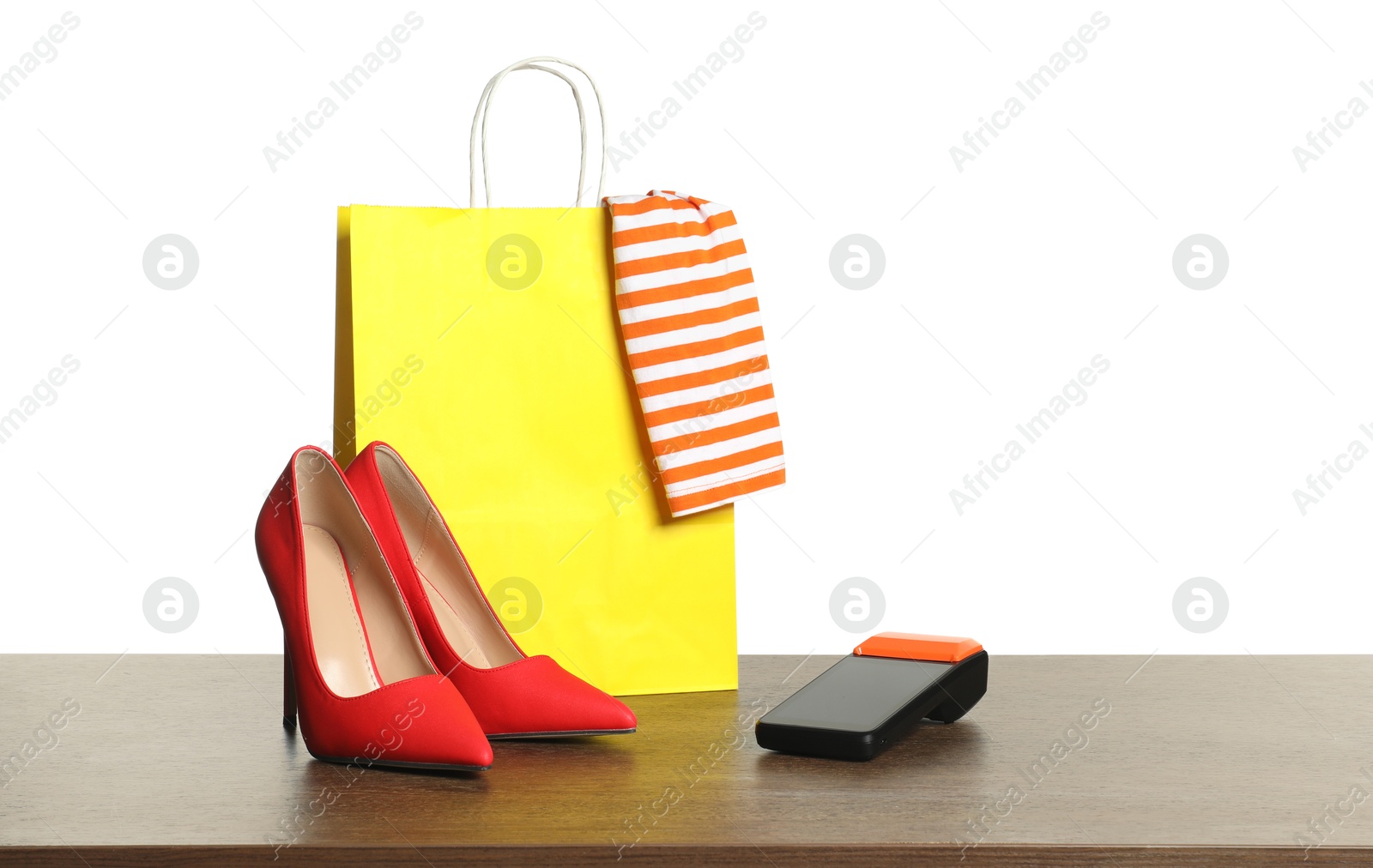 Photo of Payment terminal, shopping bag, high heeled shoes and cloth on wooden table against white background