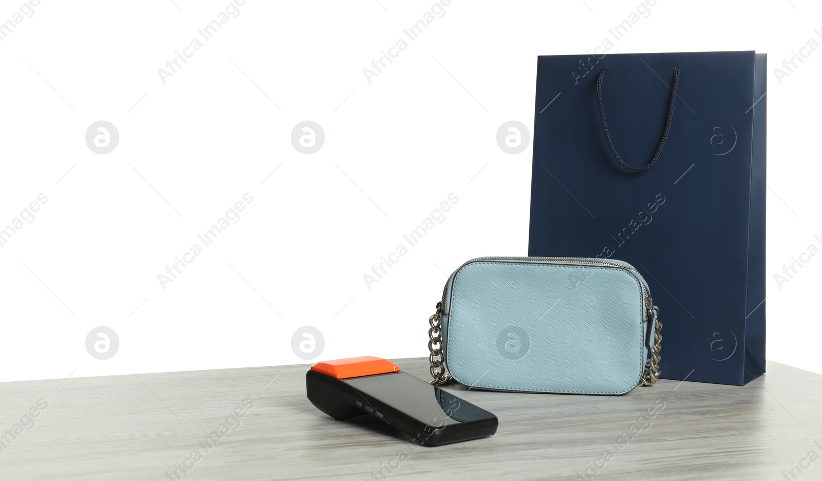 Photo of Payment terminal, purse and shopping bag on wooden table against white background