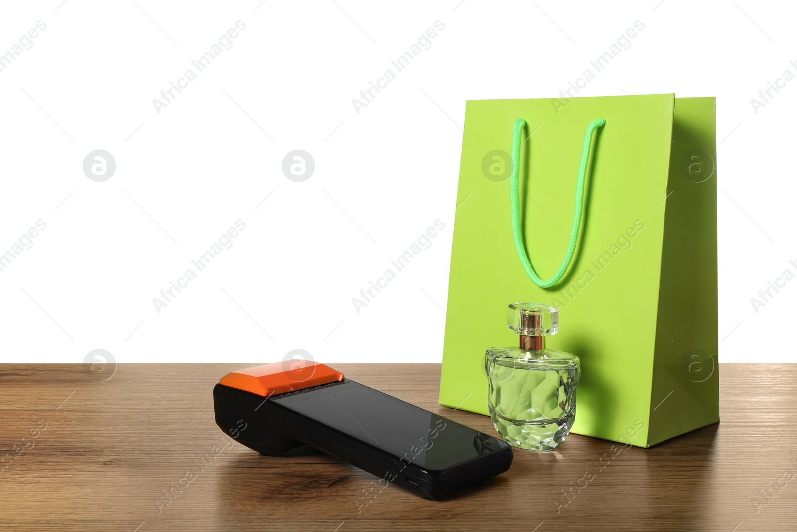 Photo of Payment terminal, perfume and shopping bag on wooden table against white background