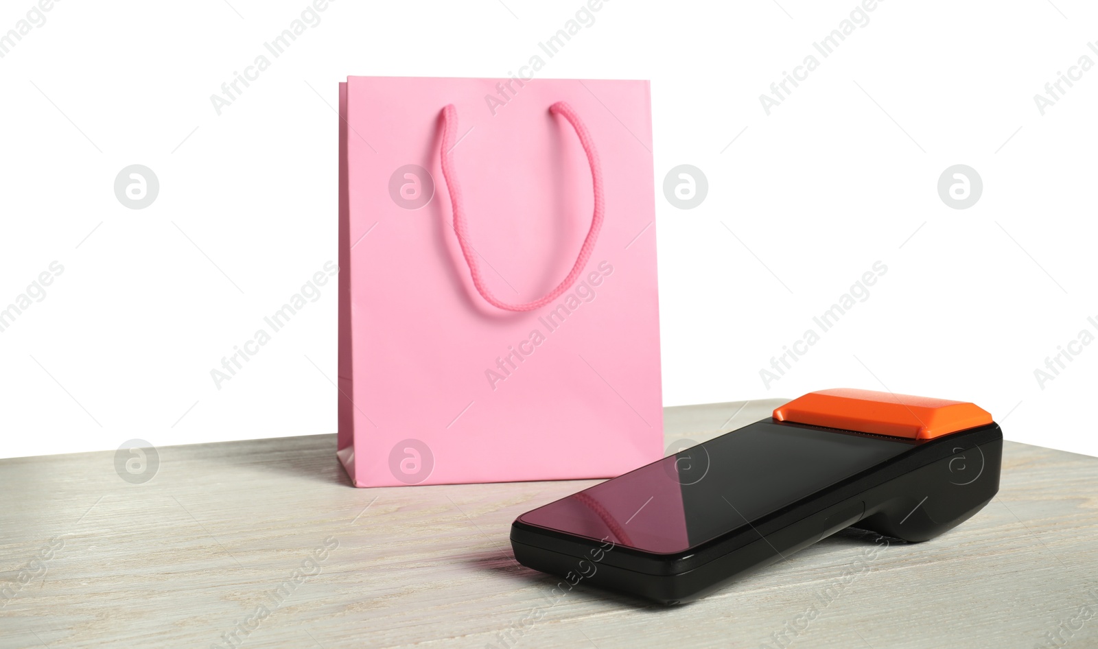 Photo of Payment terminal and shopping bag on wooden table against white background