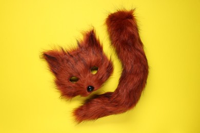 Photo of Quadrobics. Fox mask and tail on yellow background, top view