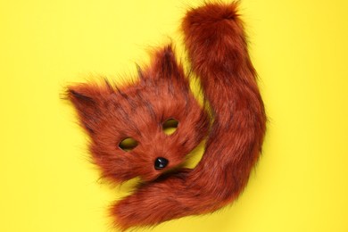 Photo of Quadrobics. Fox mask and tail on yellow background, top view