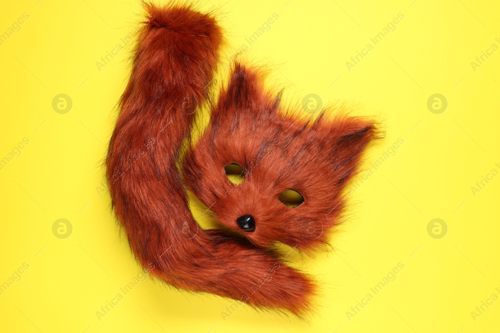 Photo of Quadrobics. Fox mask and tail on yellow background, top view