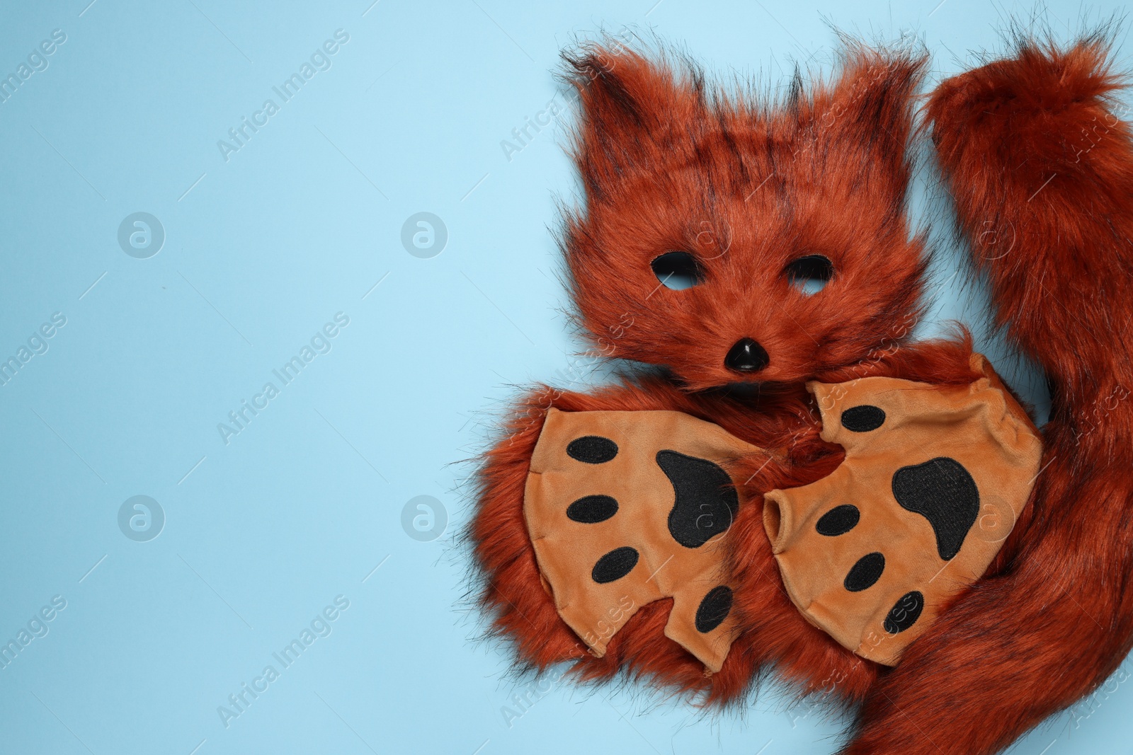 Photo of Quadrobics. Fox mask, tail and gloves on light blue background, top view. Space for text