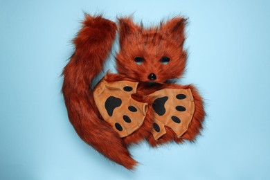 Photo of Quadrobics. Fox mask, tail and gloves on light blue background, top view