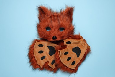 Photo of Quadrobics. Fox mask and gloves on light blue background, top view