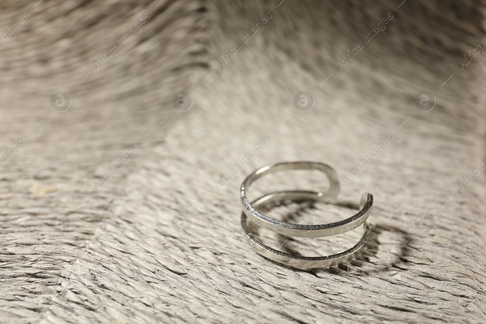 Photo of Stylish silver ring on wicker surface, closeup. Space for text