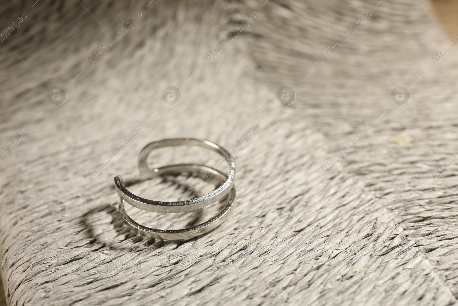 Photo of Stylish silver ring on wicker surface, closeup. Space for text