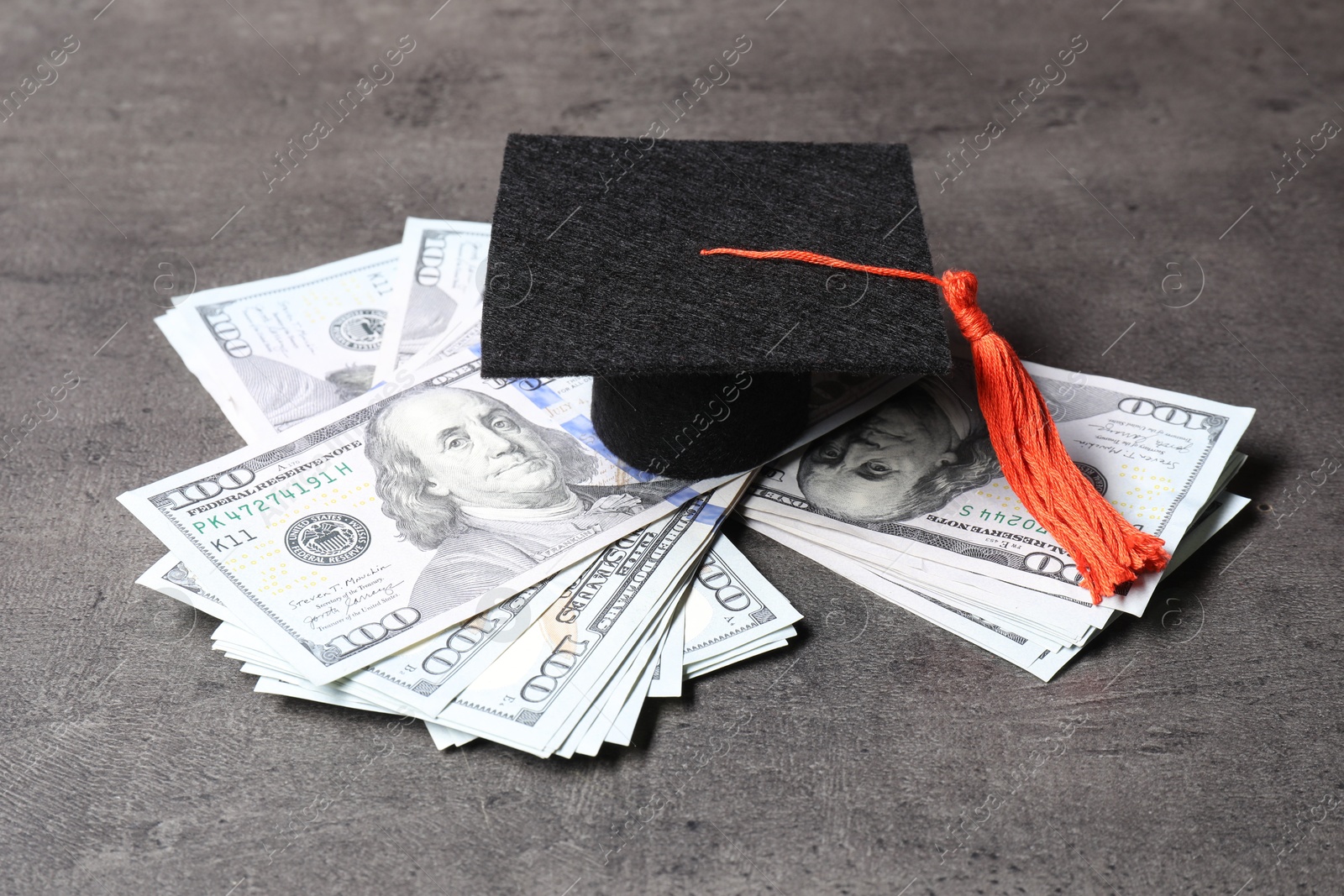 Photo of Graduate hat and dollar banknotes on grey table, closeup. Tuition payment